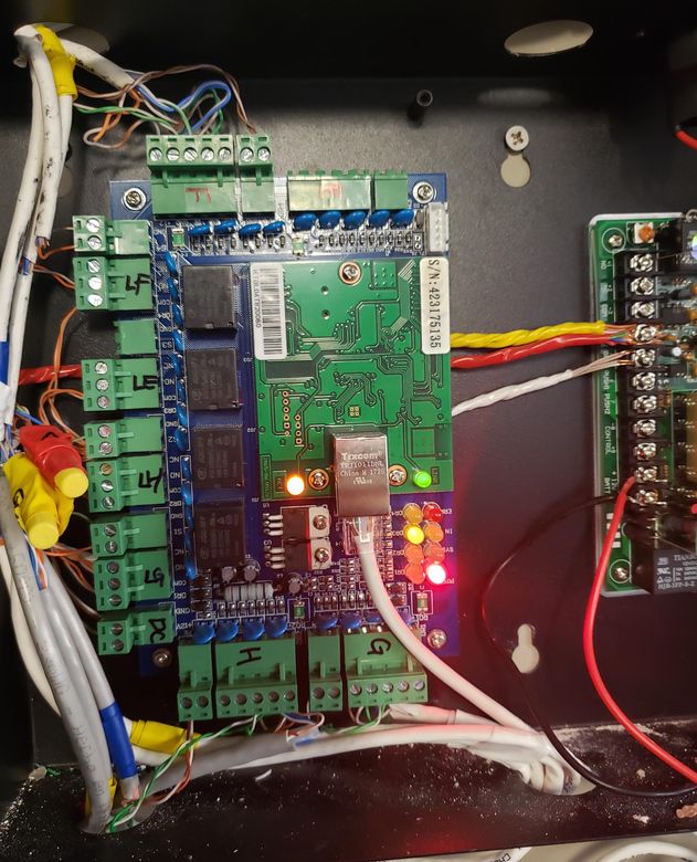 An open access control enclosure showing relay boards, terminal blocks, status LEDs and field wiring